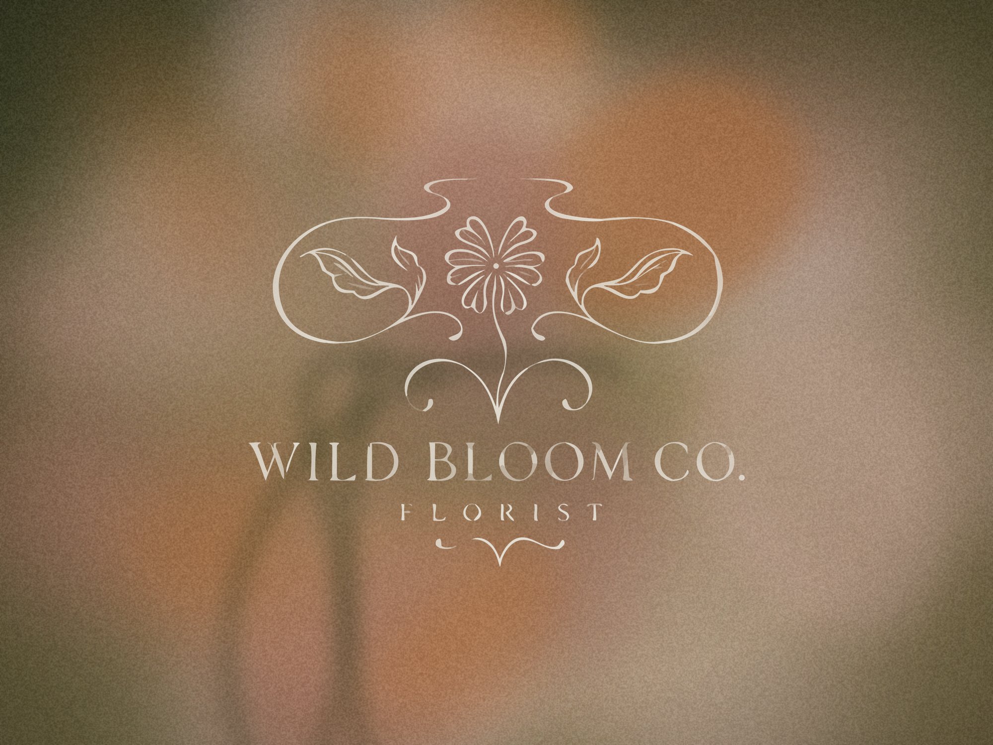 The Wild Bloom Co. logo in cream over soft-focus blush and marigold flowers